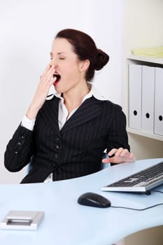 Pretty caucasian businesswoman yawning in the office.