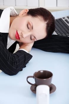Beauty caucasian businesswoman sleeping on the desk in the office.