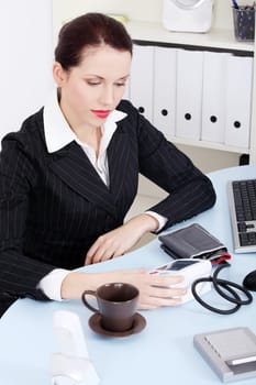 Beautiful caucasian businesswoman holding and looking at manometer sitting behind the desk in the office.
