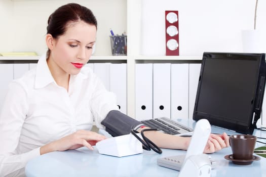 Beautiful caucasian businesswoman measuring her blood pressure in the office.