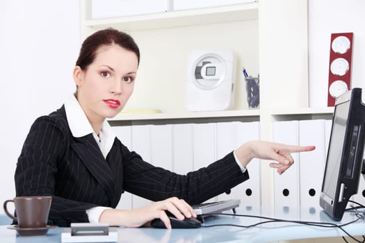 Pretty caucasian businesswoman pointing on the monitor.