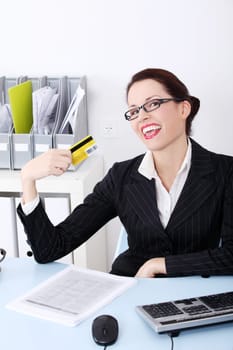 Pretty caucasian happy businesswoman holding credit card in the office.