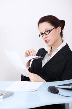 Pretty caucasian businesswoman reading files behind the desk in the office.