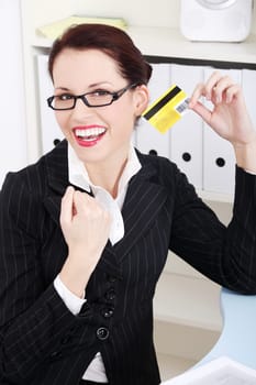 Pretty caucasian happy businesswoman holding credit card in the office.