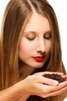 Young beautiful woman smelling coffee beans on white background