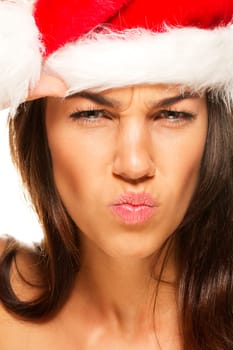 Young woman in Santa hat looking upset on white background