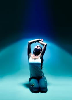 Young kneeling woman in blue spotlight