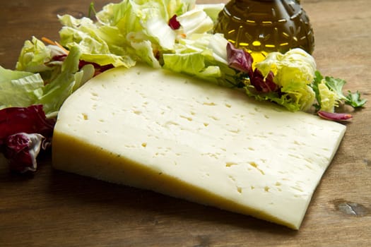 Asiago cheese with fresh salad on wooden table