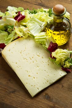 Asiago cheese with fresh salad on wooden table