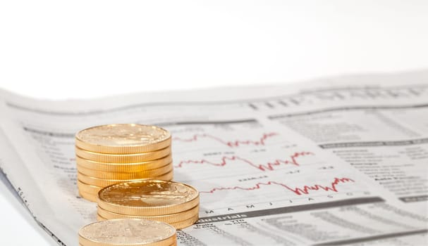 Gold Eagle one ounce coins stacked into columns on business pages of newspaper with graphs