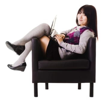 Chinese student working on a laptop while sitting in a leather chair.