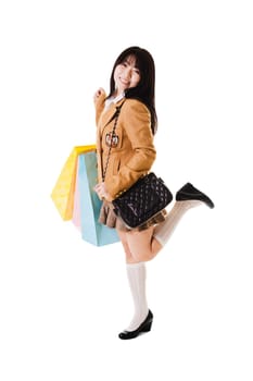 Fashionable Chinese school girl wears a shoulder bag style purse and holds shopping bags.