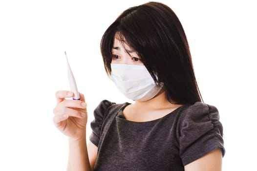 Closeup of a sick Chinese woman wearing a face mask and reading a digital thermometer.
