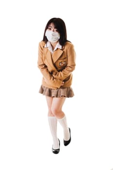 Sick Chinese school girl wearing a face mask holds her stomach in pain.