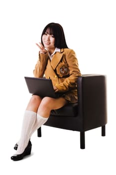Female Chinese student sitting in a chair with a laptop showing a peace sign.