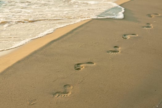 Footprints on the beach are blurred by waves