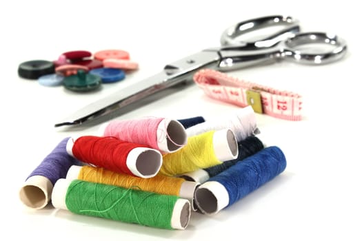 Colorful spools of thread and sewing accessories against white background