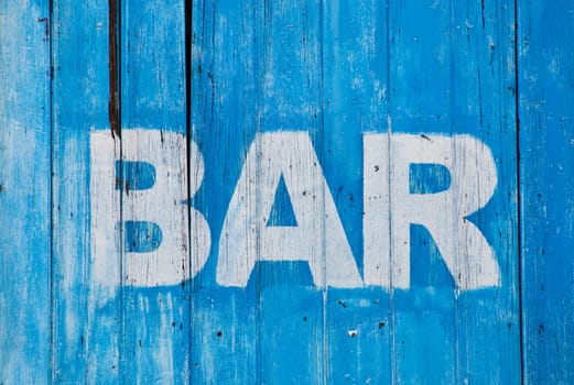 White bar sign painted on a dilapidated blue wooden wall