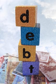 assorted childrens toy letter building blocks against a stormy background on money that spell debt