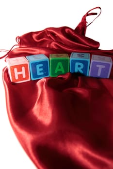 heart written with letter blocks on a silk nightie against white background