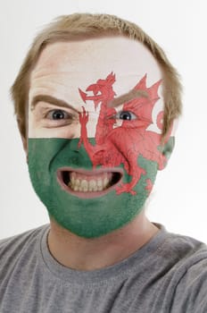 High key portrait of an angry man whose face is painted in colors of wales flag