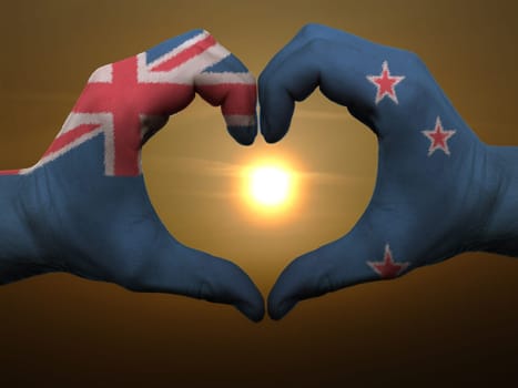 Gesture made by new zealand flag colored hands showing symbol of heart and love during sunrise