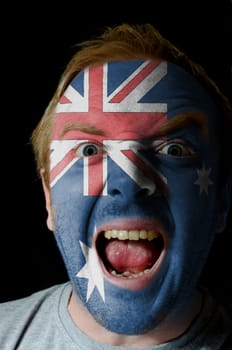 Low key portrait of an angry man whose face is painted in colors of australian flag