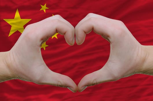 Gesture made by hands showing symbol of heart and love over china flag
