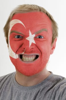 High key portrait of an angry man whose face is painted in colors of turkish flag