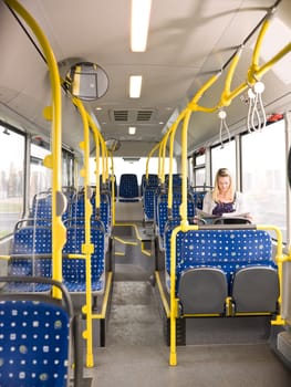Lonely woman on the bus reading a newspaper