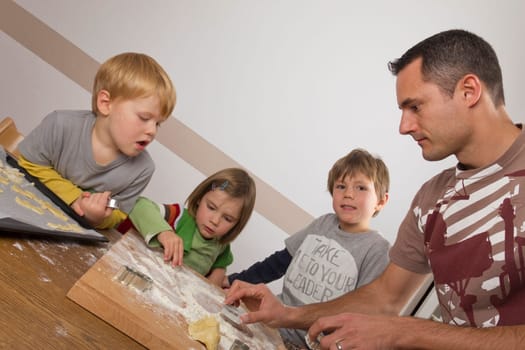 Father and children baking cookies for Christmas together