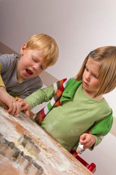 Two children cut out cookies for Christmas