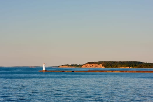 Sodus Bay Lighthouse on Lake Ontario in evening sunlight just before sunset