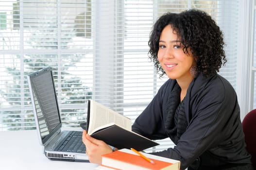 Young Woman Sat At Her Desk Using A Laptop Computer