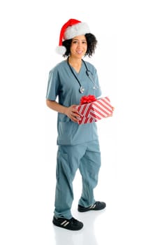 African American Hospital Nurse Holding A Christmas Gift Wearing Scrubs And a Santa Hat For The Holidays