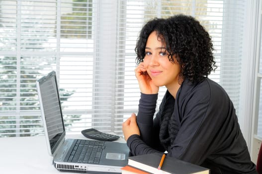 Young Woman Sat At Her Desk Using A Laptop Computer