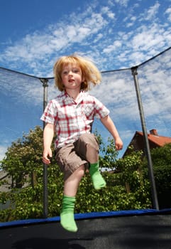 Child jumping on trampoline. toddler in garden is active playing and jump