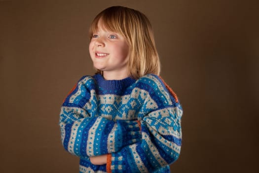 child in sweater or knit wear. cute blonde boy with long blond hair on retro brown background