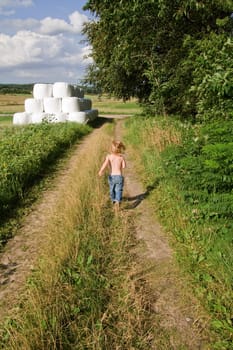 Child running down path by field or meadow. summer landscape with small boy enjoy his freedom