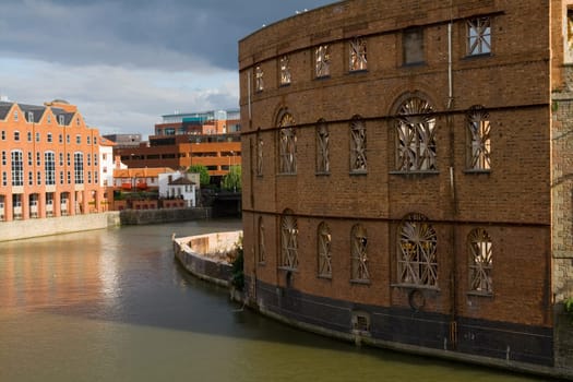 housing or development of flats by the river or canal in bristol in england. view of old building by water