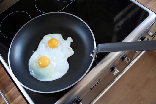 egg in frying pan. breakfast of two eggs with yellow yolks cooking on steel cooker