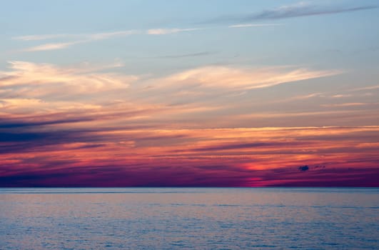 An Evening Sunset Over Water. The sky is blue at the top and purple closer to the water