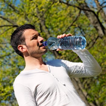 man drinking water after sport in a park