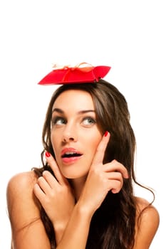 Brunette woman pointing with fingers at the gift on her head on white background