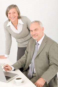 Professional businesspeople behind office table with laptop