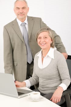 Professional businesspeople behind office table with laptop