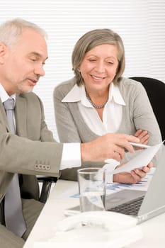 Professional elegant happy senior businesswoman looking graphs with man colleague