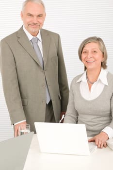 Professional senior businessman looking at computer with woman colleague