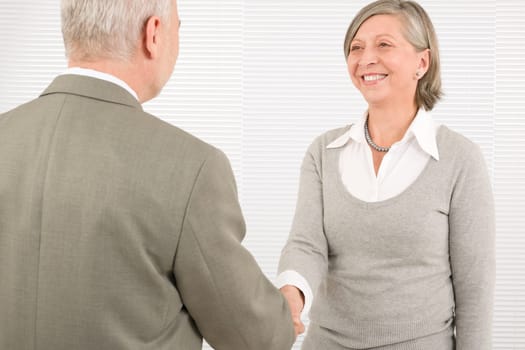 Professional elegant smiling senior businesswoman welcoming mature businessman