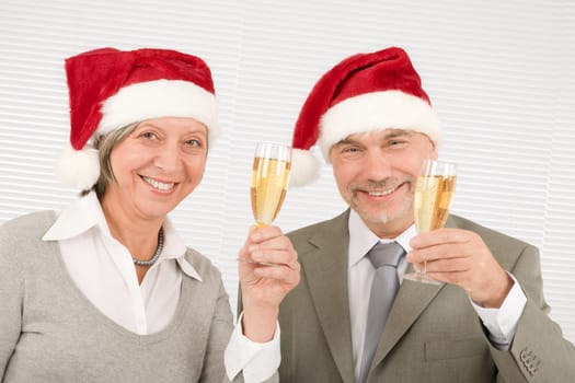 Laughing senior businesspeople wear Christmas Santa hat drink champagne